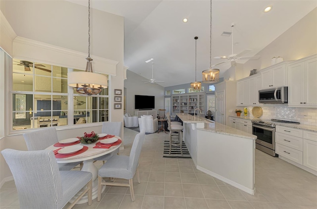 kitchen featuring pendant lighting, white cabinets, stainless steel appliances, and an island with sink