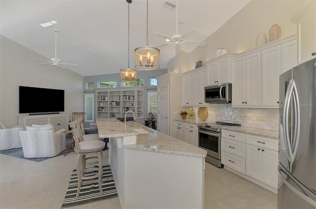 kitchen featuring white cabinetry, high vaulted ceiling, an island with sink, and appliances with stainless steel finishes