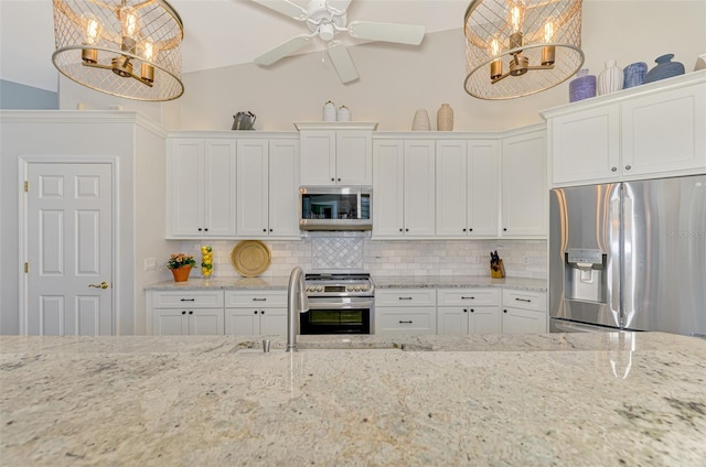 kitchen with light stone countertops, hanging light fixtures, stainless steel appliances, vaulted ceiling, and white cabinets