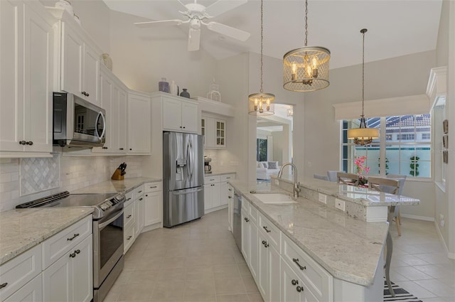 kitchen featuring a kitchen breakfast bar, stainless steel appliances, sink, a center island with sink, and high vaulted ceiling