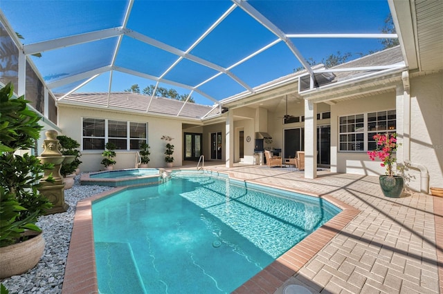 view of pool featuring a ceiling fan, a pool with connected hot tub, glass enclosure, and a patio