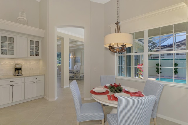 dining area featuring baseboards, a chandelier, ornamental molding, and light tile patterned flooring