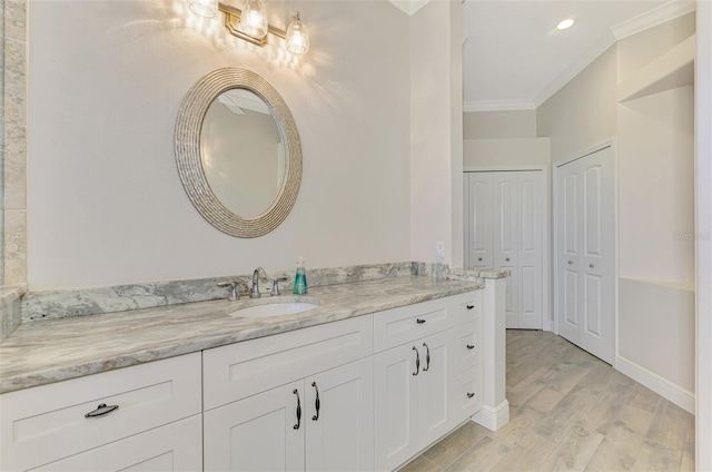 bathroom featuring vanity, baseboards, crown molding, and wood finished floors