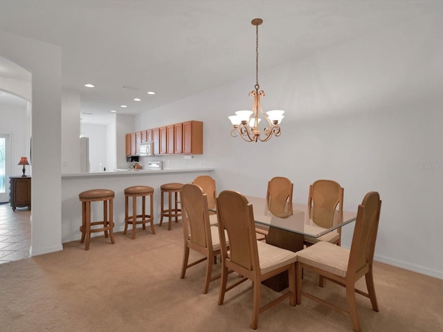 dining area with light carpet and a chandelier