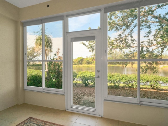 entryway with light tile patterned flooring, a water view, and a wealth of natural light