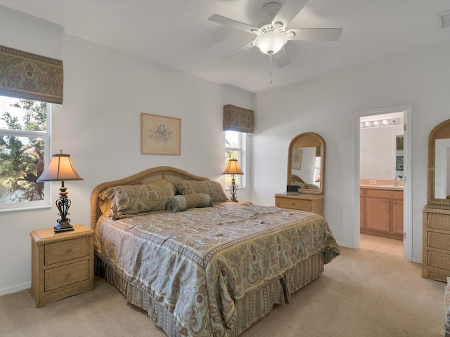 bedroom featuring ceiling fan, light colored carpet, and ensuite bathroom