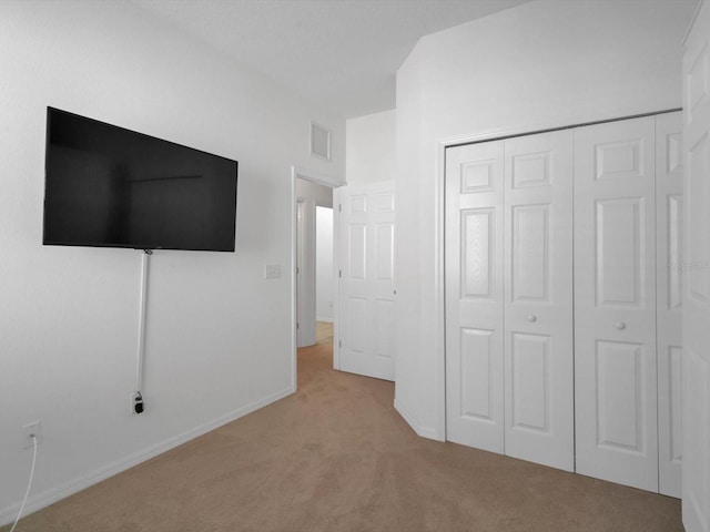 unfurnished bedroom featuring light colored carpet and a closet