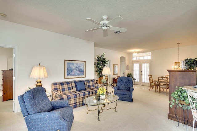 living room featuring ceiling fan, light colored carpet, a textured ceiling, and french doors