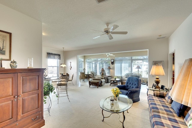 living room with a textured ceiling, ceiling fan, and light carpet