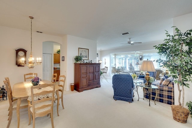 carpeted dining space with ceiling fan with notable chandelier