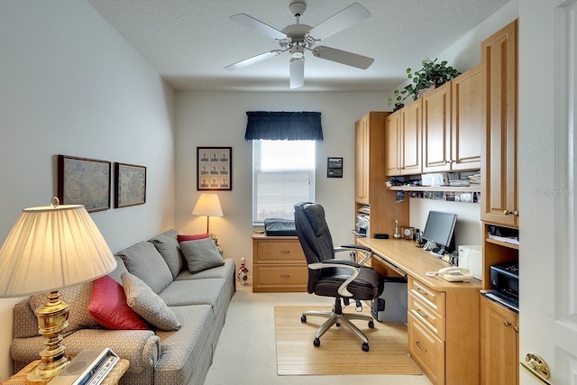 office area featuring a textured ceiling, light colored carpet, ceiling fan, and built in desk