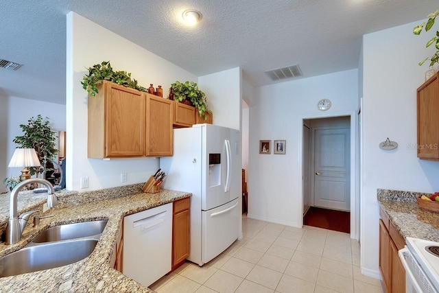 kitchen with sink, light stone counters, a textured ceiling, white appliances, and light tile patterned floors