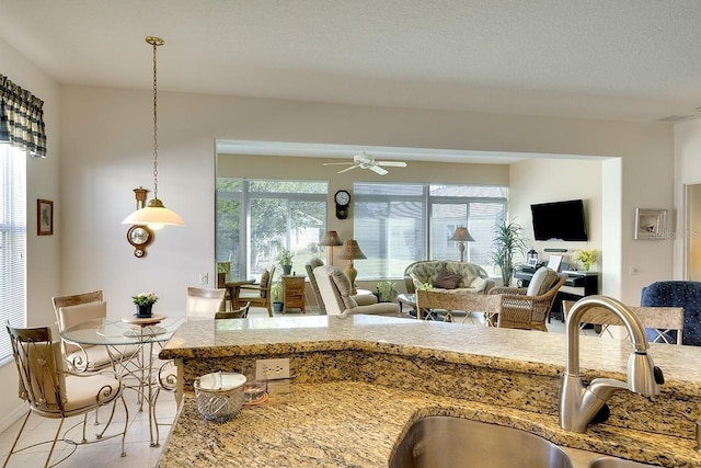 kitchen featuring ceiling fan, sink, light tile patterned floors, and hanging light fixtures