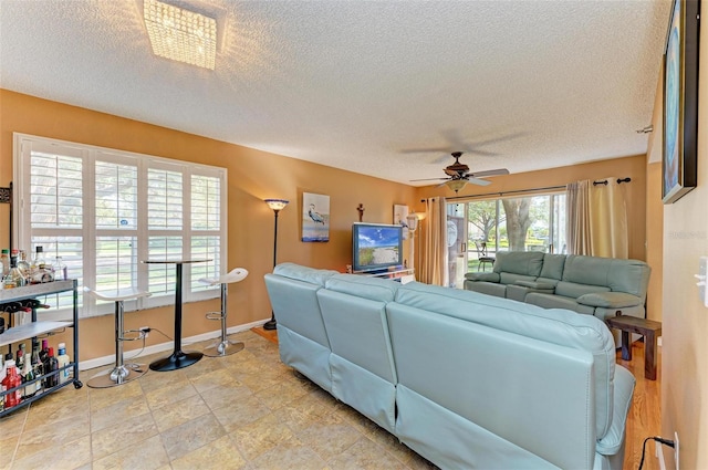 living room featuring ceiling fan, a textured ceiling, and a wealth of natural light