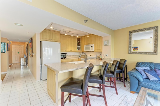 kitchen with sink, kitchen peninsula, a textured ceiling, white appliances, and a breakfast bar