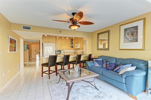 tiled living room featuring a textured ceiling and ceiling fan