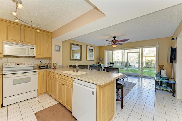 kitchen featuring kitchen peninsula, a textured ceiling, white appliances, sink, and a breakfast bar area