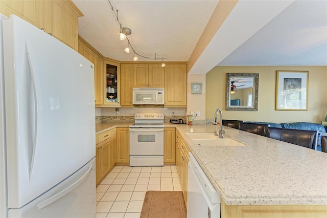 kitchen with a textured ceiling, sink, white appliances, and light brown cabinets