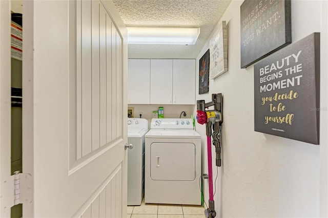 laundry area with cabinets, light tile patterned floors, washing machine and dryer, and a textured ceiling