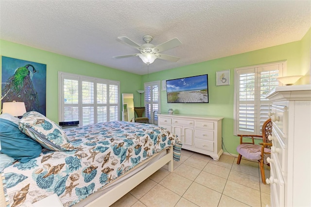 tiled bedroom featuring multiple windows, a textured ceiling, and ceiling fan