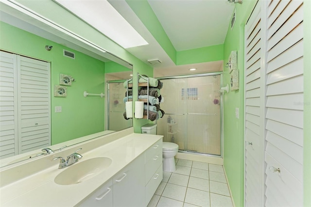 bathroom featuring tile patterned floors, vanity, toilet, and a shower with door