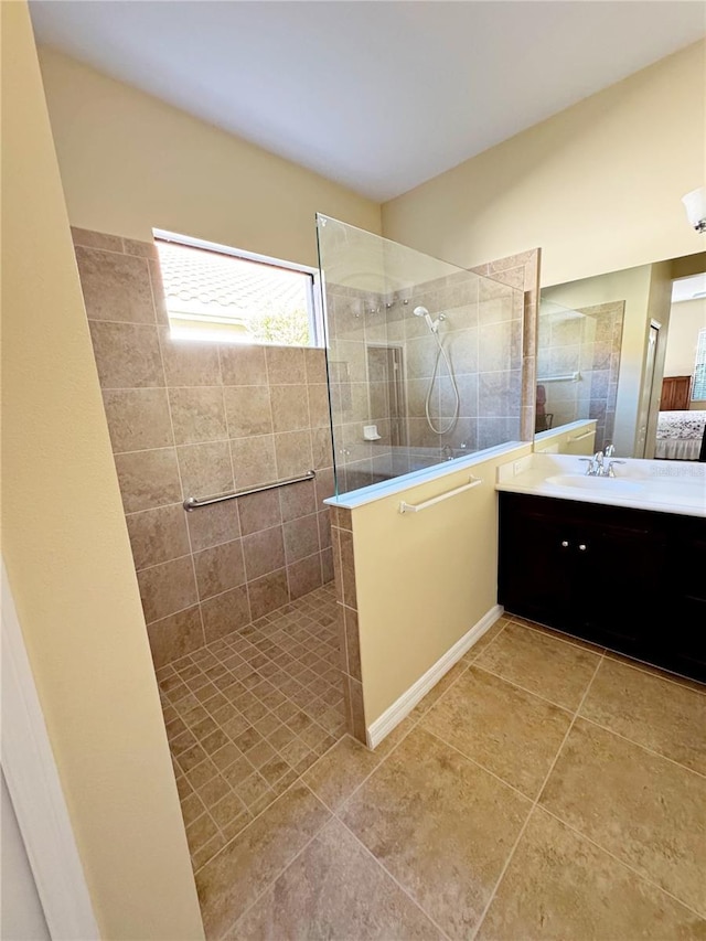 bathroom featuring tile patterned flooring, vanity, and a tile shower