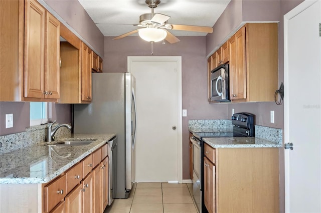 kitchen with appliances with stainless steel finishes, light stone counters, ceiling fan, sink, and light tile patterned floors