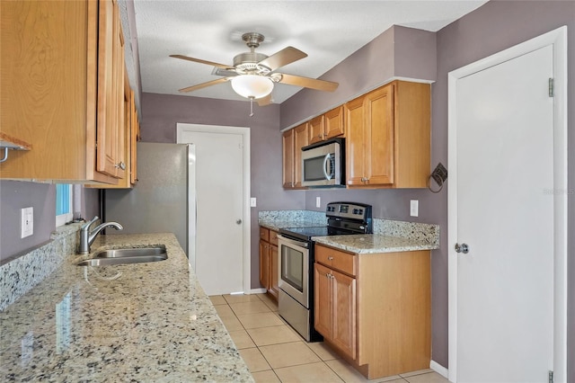 kitchen featuring sink, ceiling fan, light tile patterned floors, appliances with stainless steel finishes, and light stone counters