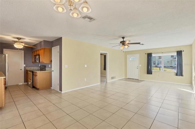 unfurnished living room with ceiling fan with notable chandelier, light tile patterned flooring, and a textured ceiling