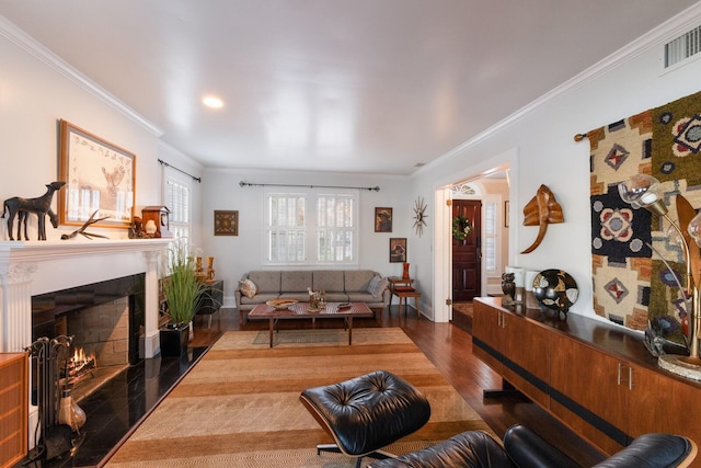 living room with dark wood finished floors, visible vents, ornamental molding, a lit fireplace, and baseboards