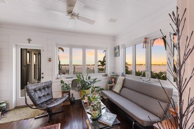 sunroom featuring ceiling fan and a water view