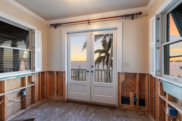 doorway featuring a water view, french doors, wainscoting, dark wood-style floors, and crown molding