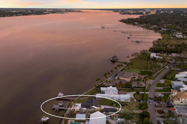 aerial view at dusk featuring a water view