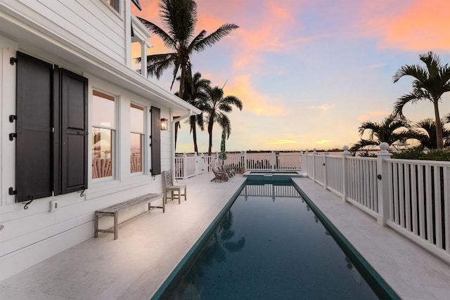 pool at dusk featuring a fenced in pool and a patio