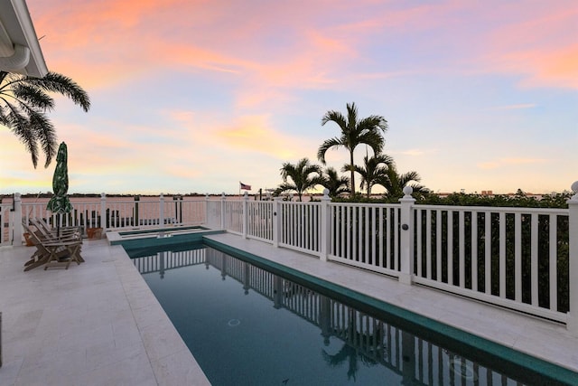 pool at dusk featuring a patio area and a fenced in pool