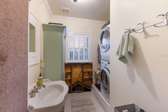 bathroom featuring tile patterned floors, crown molding, stacked washer / drying machine, and sink