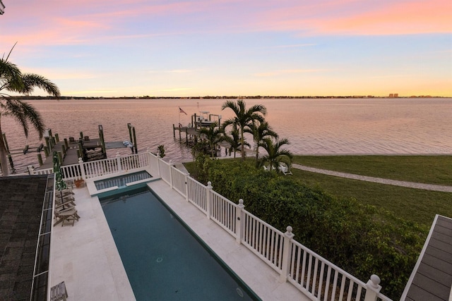 pool at dusk featuring a water view, a dock, and a patio area