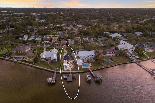 aerial view at dusk featuring a water view and a residential view