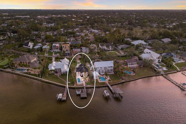 aerial view at dusk with a water view and a residential view