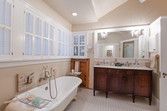 bathroom featuring a soaking tub, vaulted ceiling, an inviting chandelier, and vanity