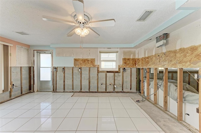 interior space with light tile patterned floors, a textured ceiling, and ceiling fan