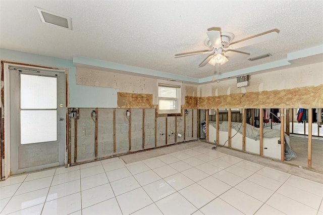 empty room with ceiling fan, light tile patterned floors, and a textured ceiling