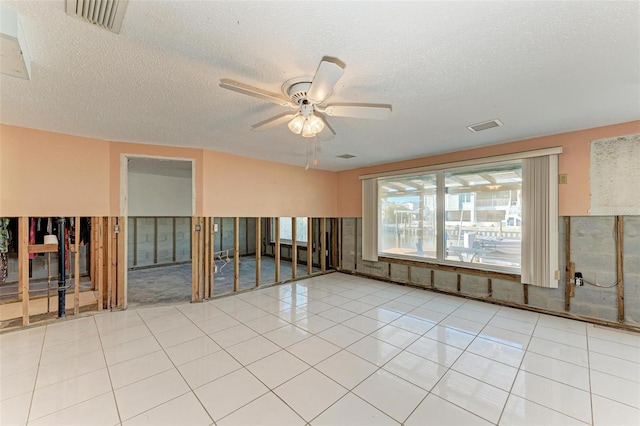 tiled spare room with ceiling fan and a textured ceiling