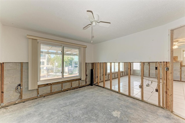 empty room with ceiling fan and a textured ceiling