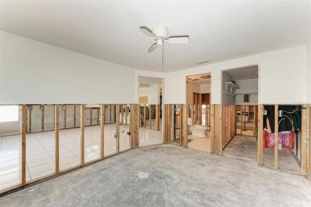 empty room with carpet flooring, ceiling fan, and a textured ceiling