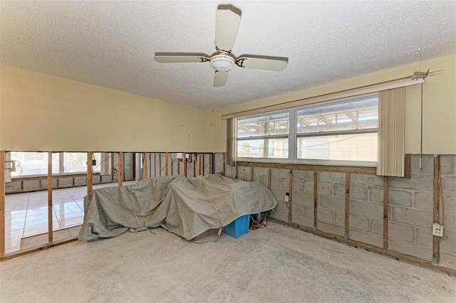 bedroom featuring multiple windows, ceiling fan, and a textured ceiling