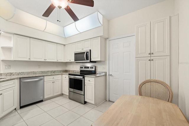 kitchen with light tile patterned floors, stainless steel appliances, white cabinetry, and ceiling fan