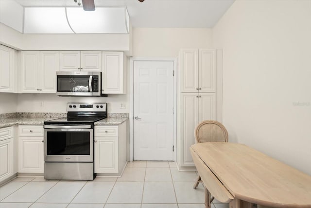 kitchen featuring light stone countertops, light tile patterned floors, white cabinetry, and appliances with stainless steel finishes