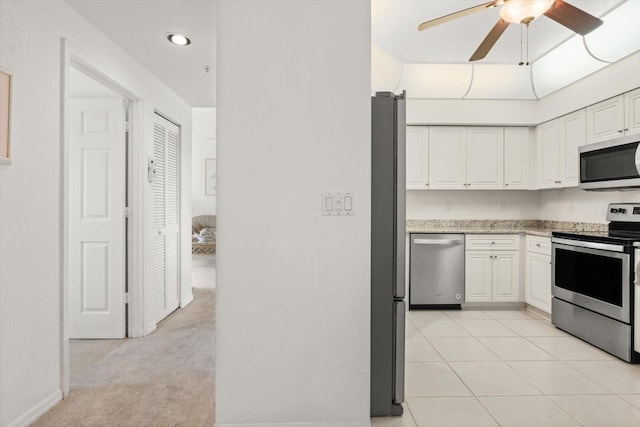 kitchen featuring white cabinets, appliances with stainless steel finishes, light colored carpet, and ceiling fan