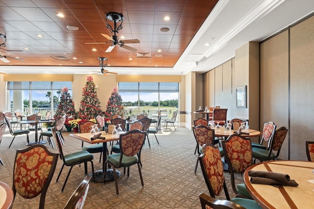 carpeted dining room with plenty of natural light, ceiling fan, crown molding, and a tray ceiling